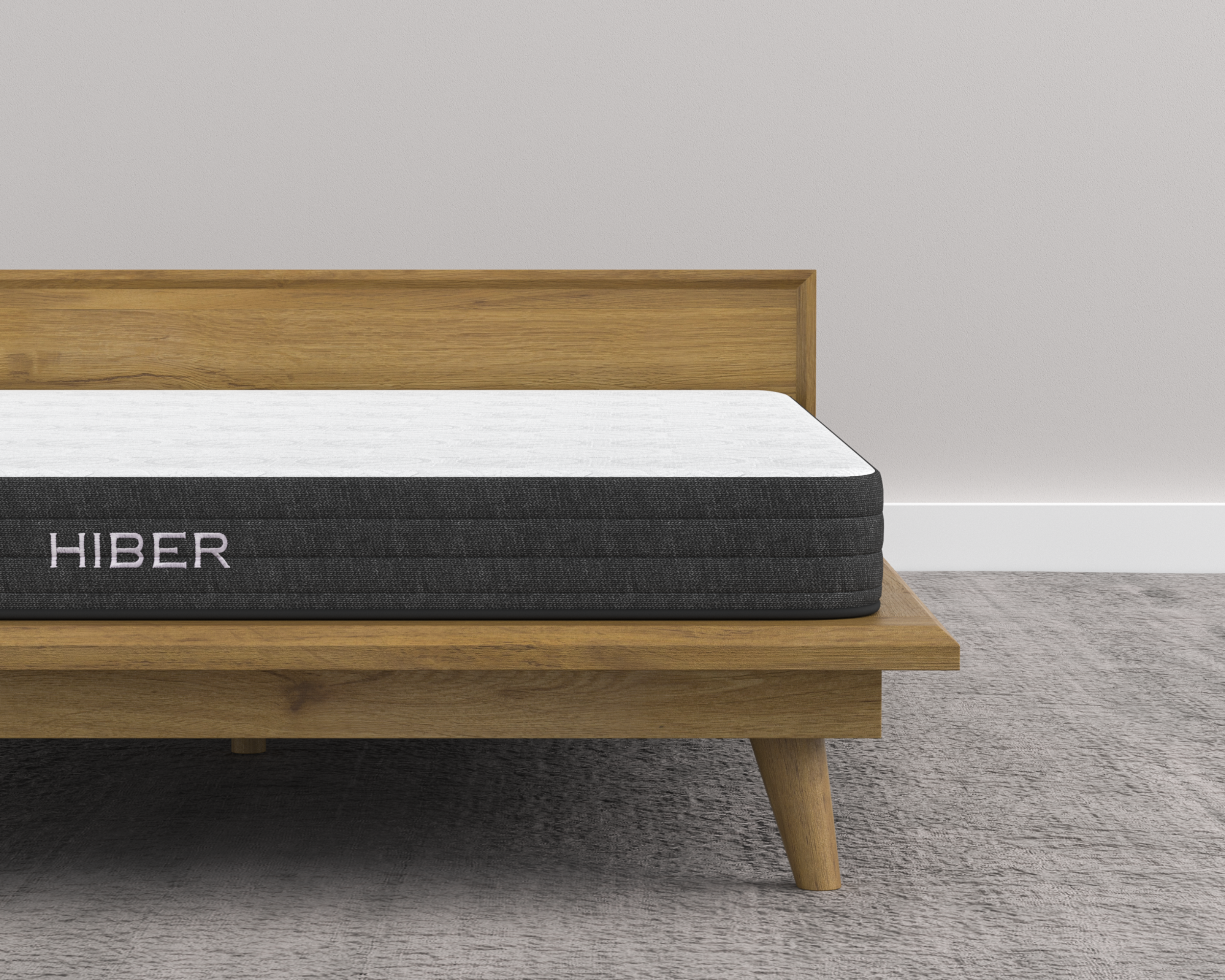 Hiber mattress on a wooden bed frame with a plain background