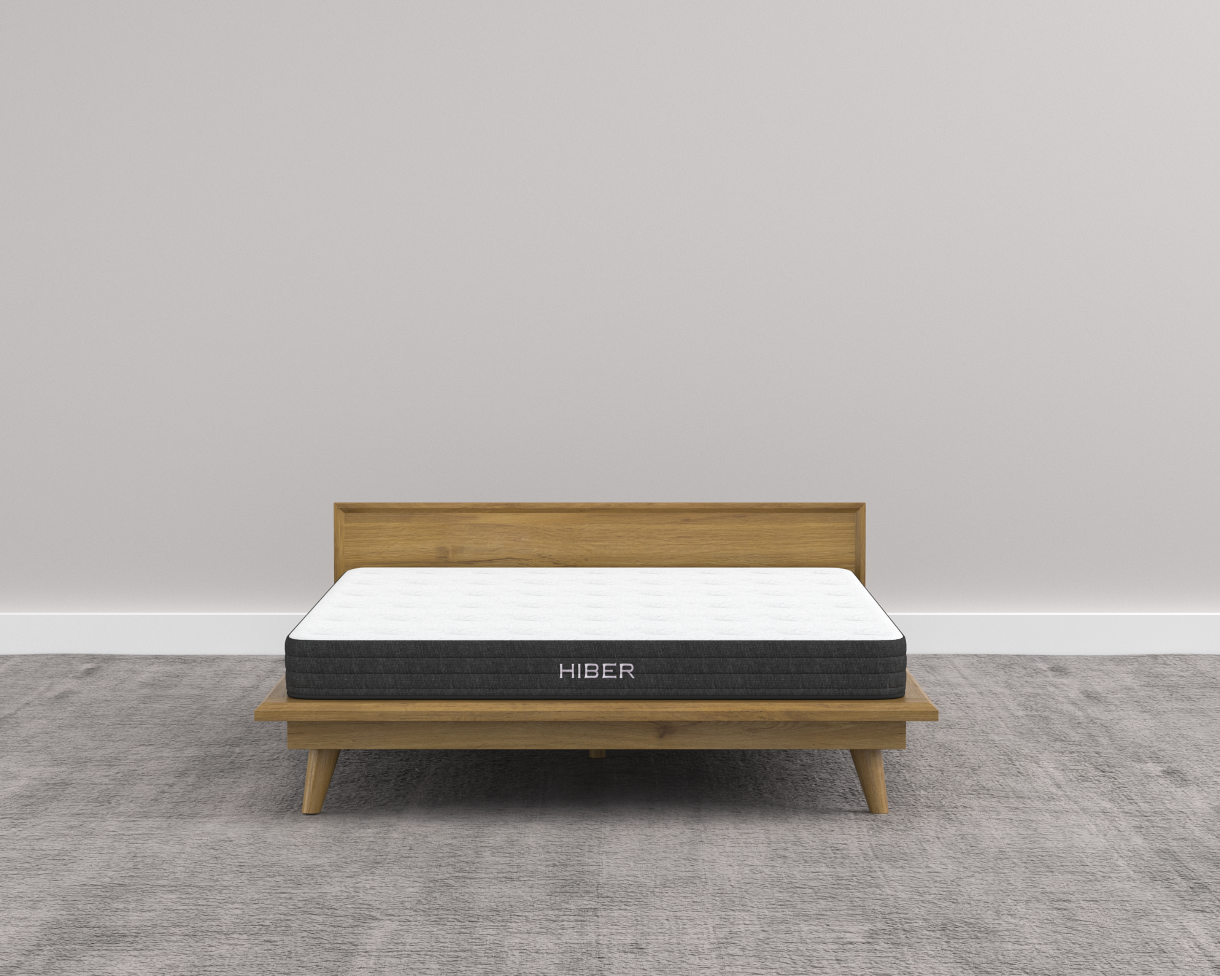 Mattress on a wooden bed frame with 'Hiber' branding against a plain wall.
