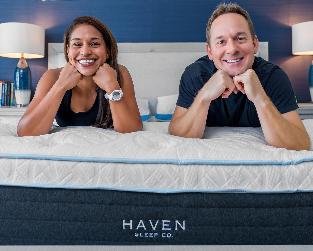 Two people lying on a Haven mattress in a bedroom setting.