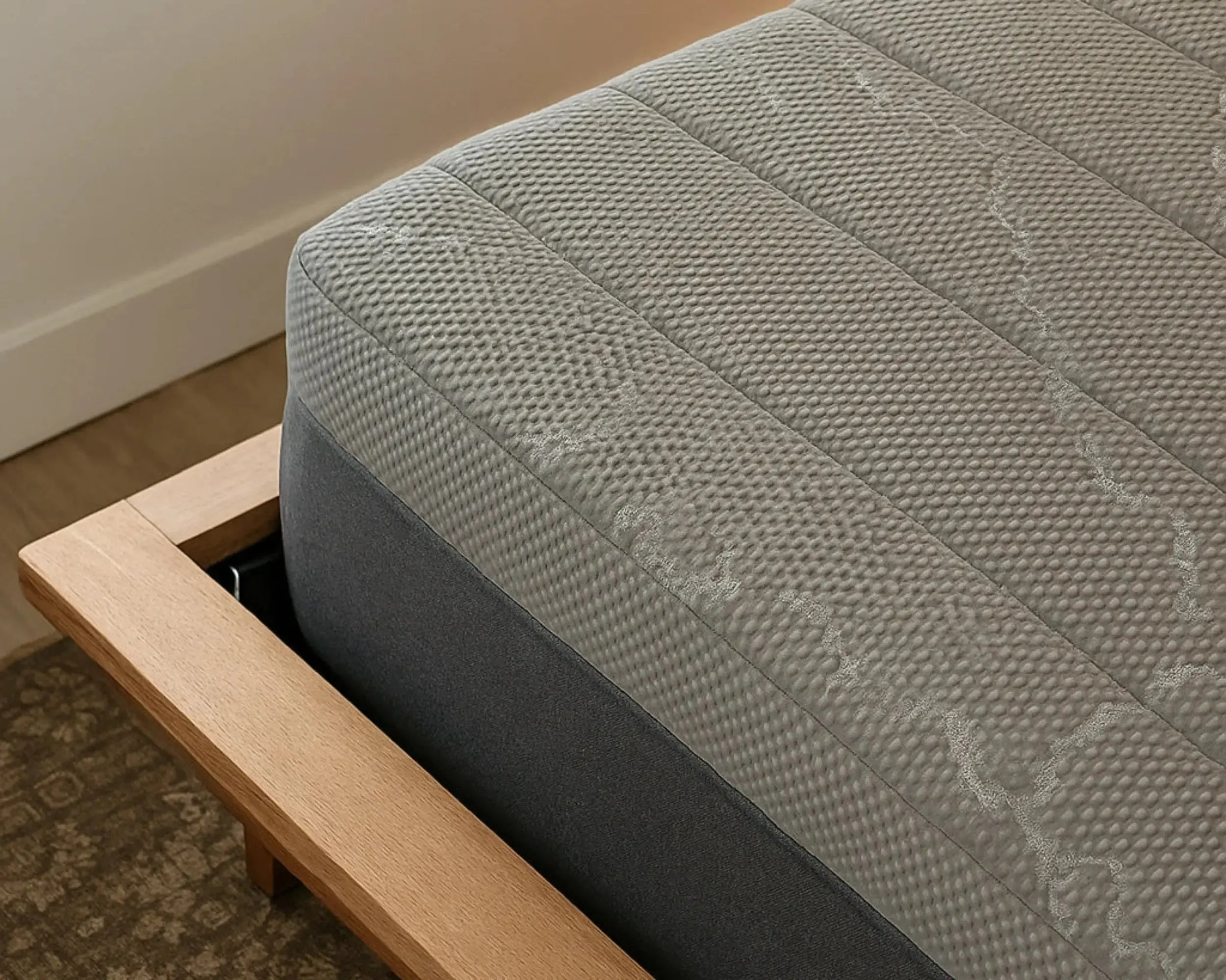 Gray mattress with wooden frame on a carpeted floor