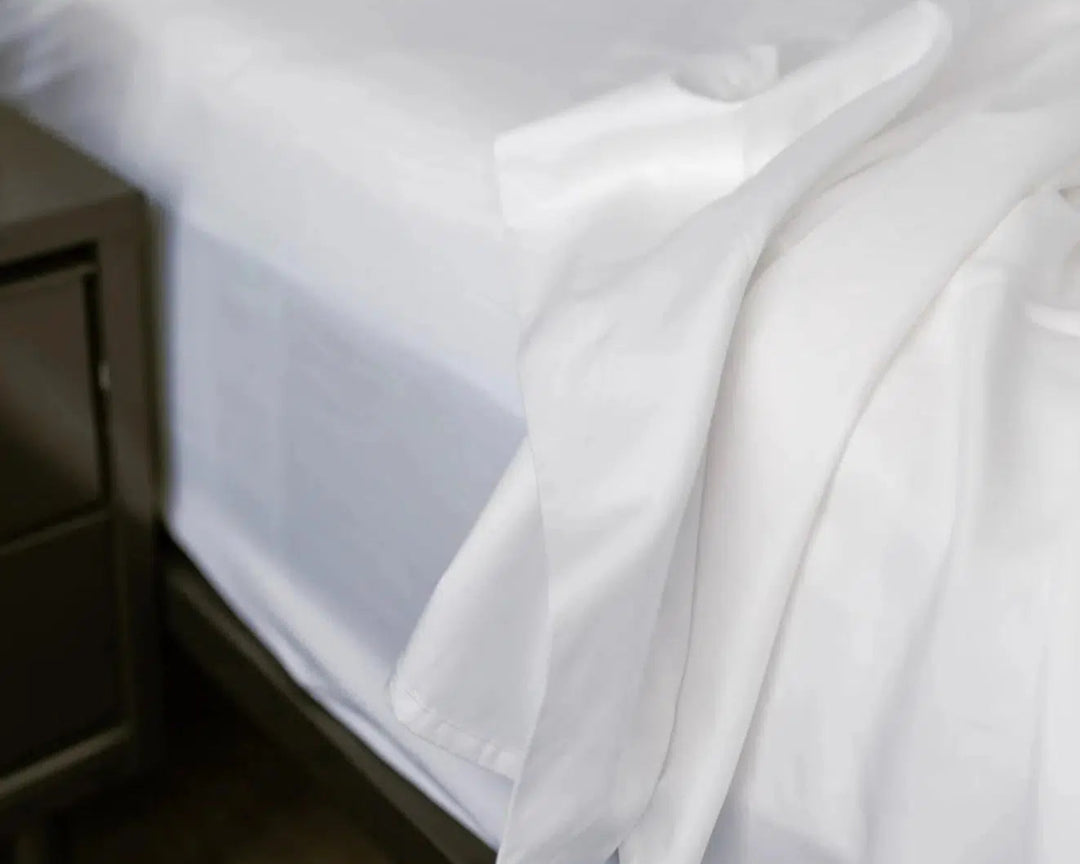 Close-up of the luxurious Bedface Percale Sheets draped over a mattress, part of the Haven Sleep Co.'s Side Sleeper Bundle. The crisp white sheets, made from premium, breathable fabric, are designed to enhance the comfort of your sleeping experience. The image highlights the smooth, soft texture of the sheets, emphasizing their quality and how they contribute to a cool, comfortable sleep environment for side sleepers.