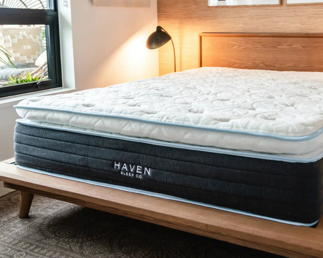 Haven LUX Pillowtop Hybrid mattress displayed in a modern bedroom setting with natural light and minimalist decor