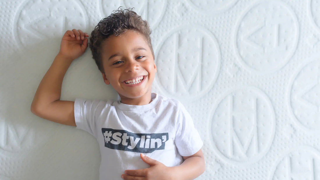 Smiling young child lying on a white quilted mattress, highlighting comfort and safety for kids.
