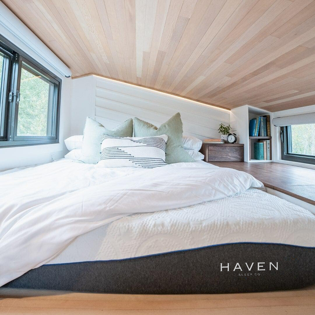 Cozy bedroom loft with a low ceiling featuring the Haven Rejuvenate Plush all-foam mattress, dressed in white bedding and styled with soft pillows—ideal for side sleepers seeking comfort and support.