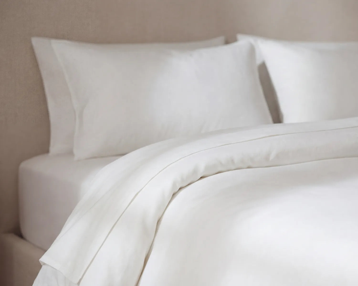 White bedding set with pillows on a neutral background
