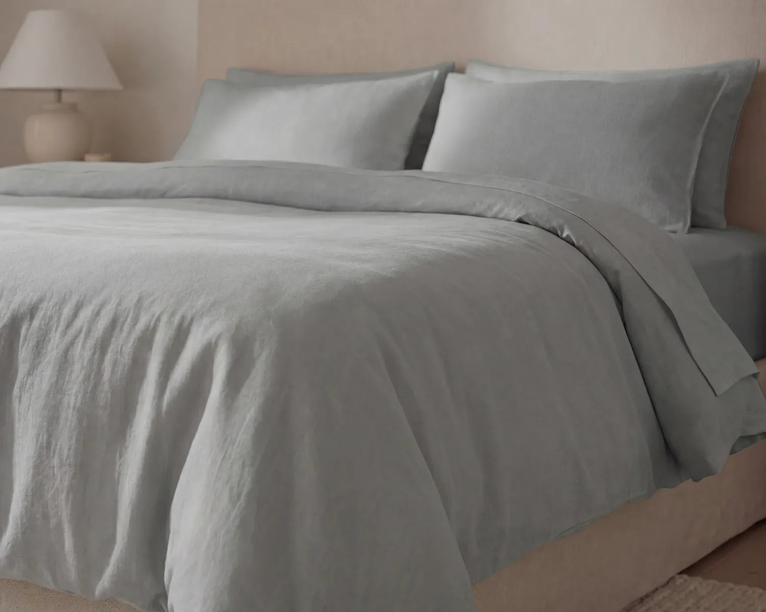 Gray bedding set on a bed with a neutral-colored wall in the background