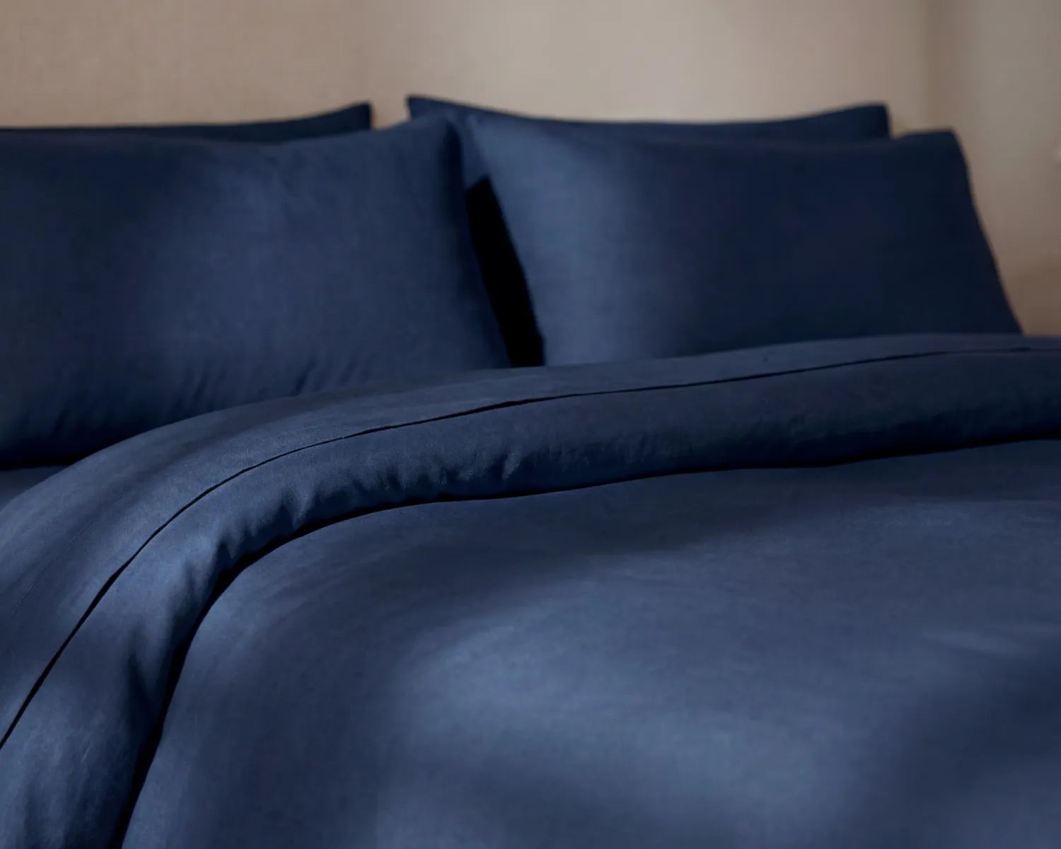 Navy blue bedding set with pillows on a neutral background