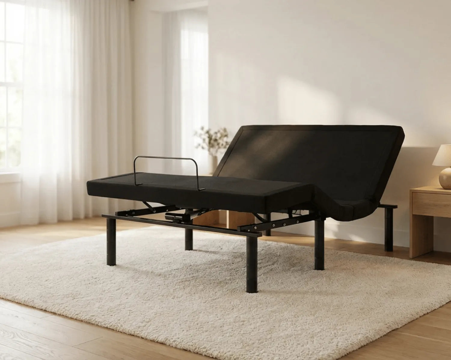 Black adjustable bed in a room with light-colored walls and wooden flooring.