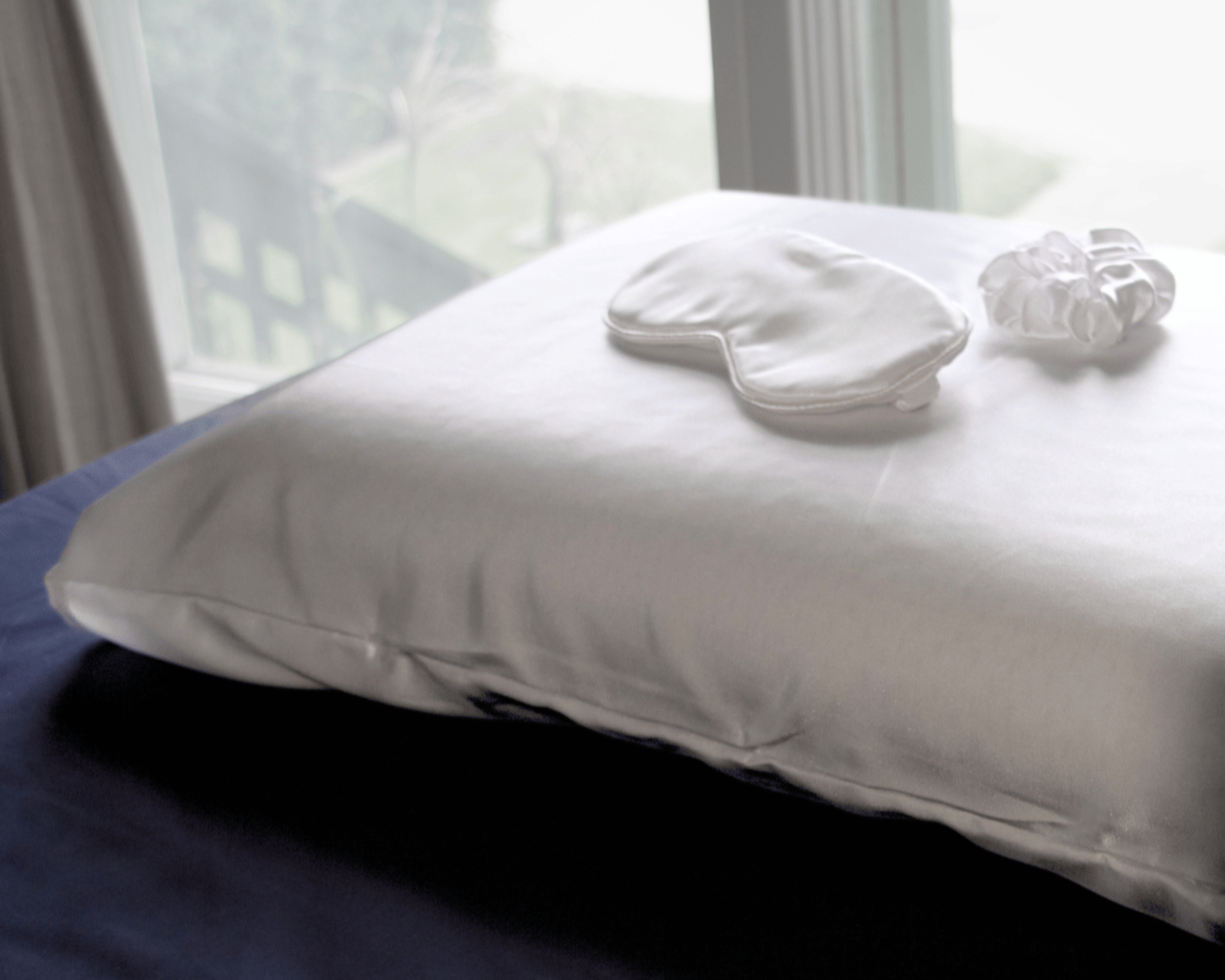 Silk sleep mask and scrunchie from the Haven Clean Sleep Bundle resting on a silk pillowcase, highlighting luxurious and comfortable sleep accessories