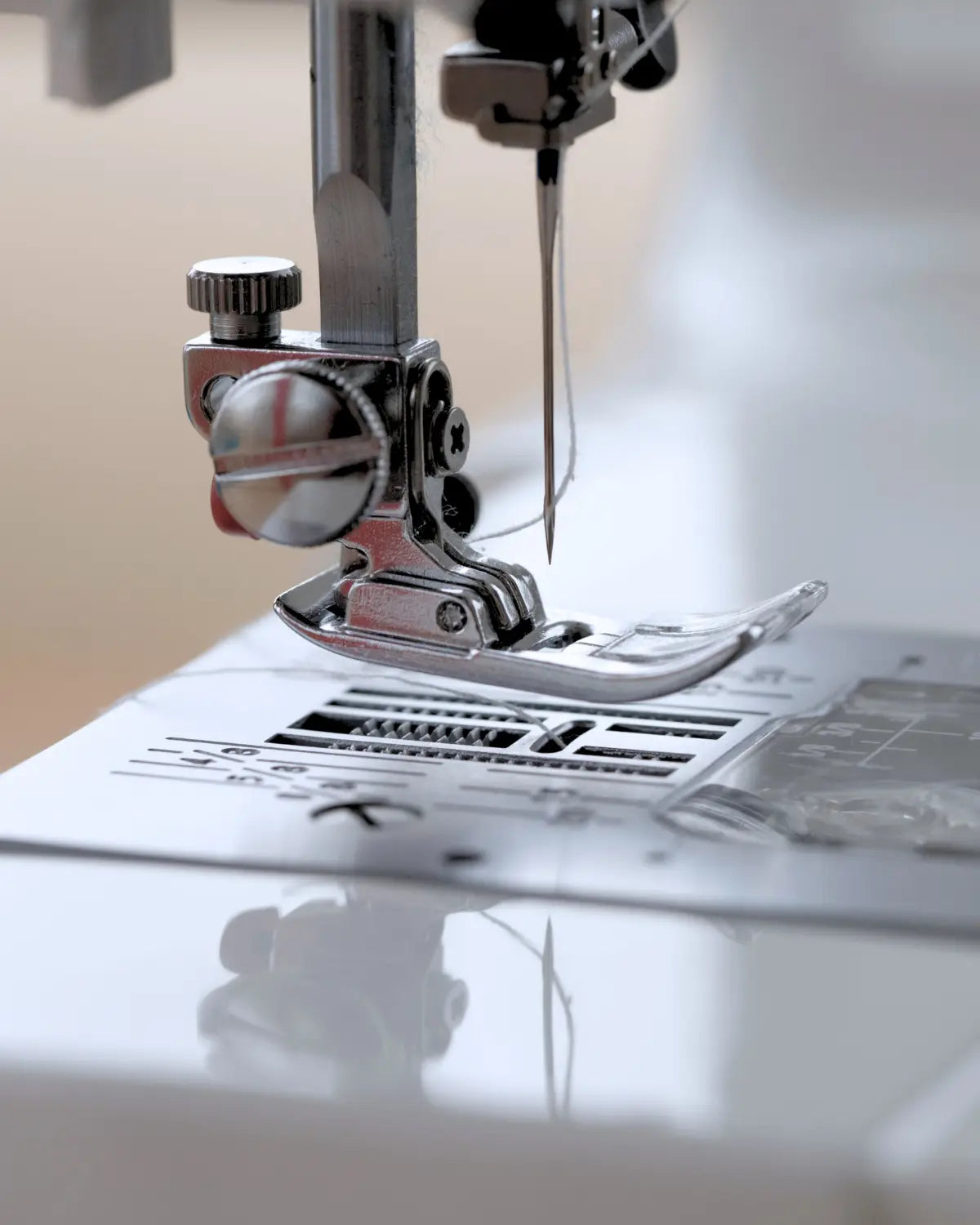 Close-up of a sewing machine needle and presser foot on a white background