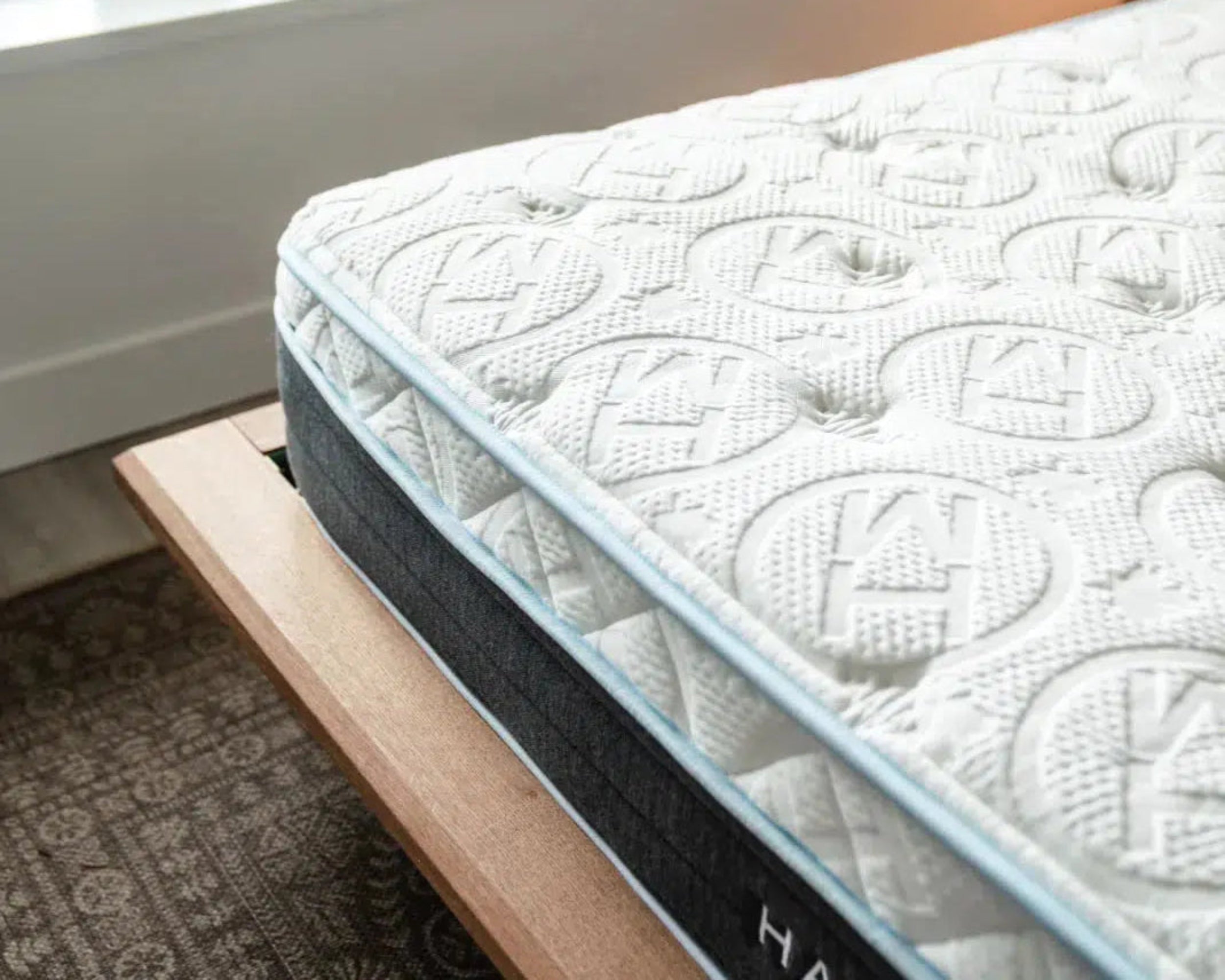 Close-up of the Haven Eurotop Hybrid mattress on a wooden bed frame, highlighting the detailed stitching and cool-to-the-touch fabric for enhanced sleep comfort