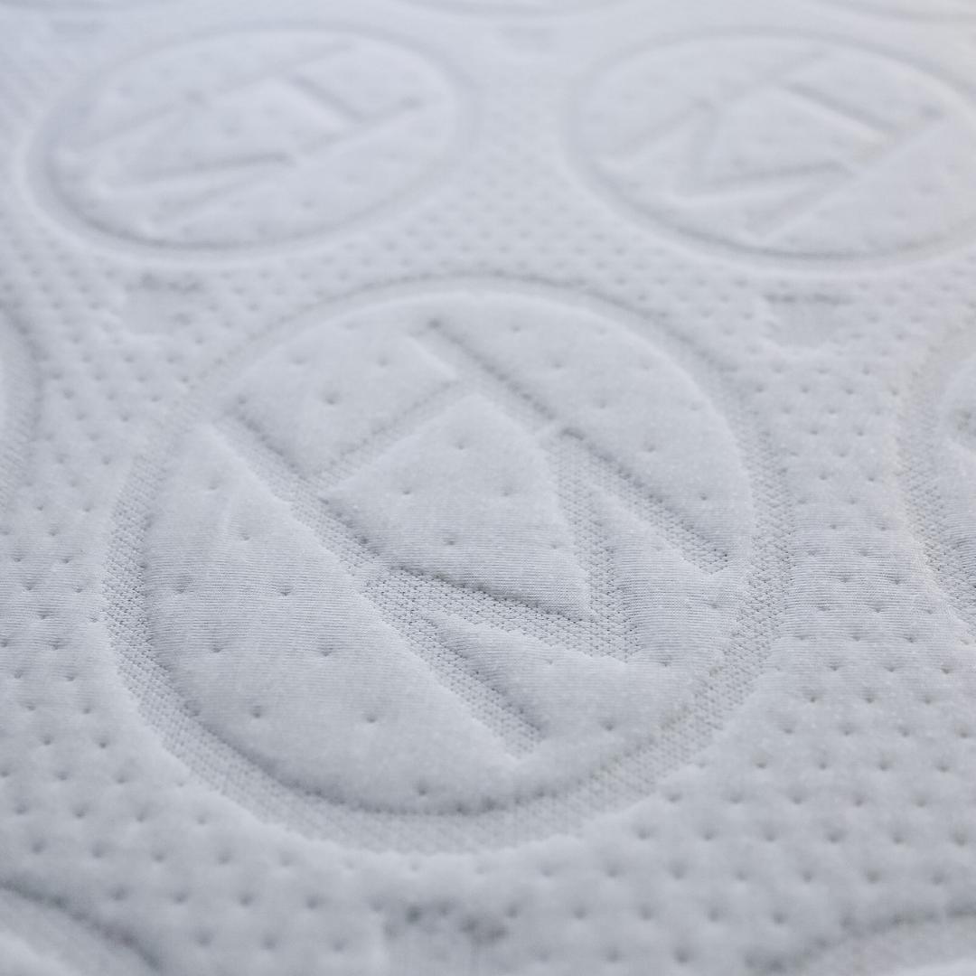A closeup shot of an H and M letter encapsulated by a circle embroidered on a mattress.