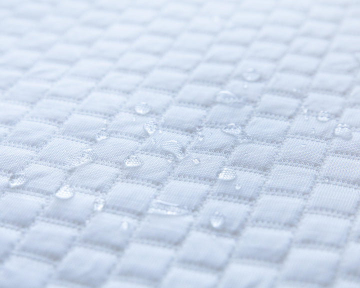 close up of water droplets on top of a Bedface Artic Cooling Mattress protector showcasing that it is waterproof