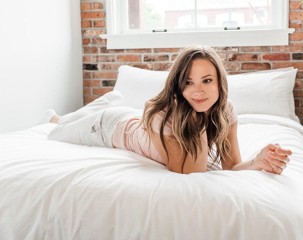 Woman in white laying across Haven Mattress with Starlight White bedding 