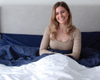 Woman sitting up in bed smiling in Bedface premium sheet set and duvet cover - starlight white and night time navy
